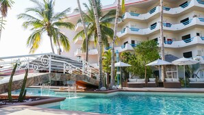 A pool area with a bridge, palm trees, and lounge chairs. - The Westmarine Waterfront Hotel (La Paz)