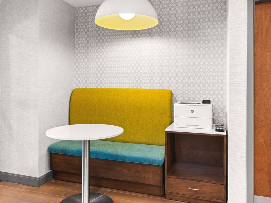 A corner with a wooden bench, a small table, and a printer on a shelf.