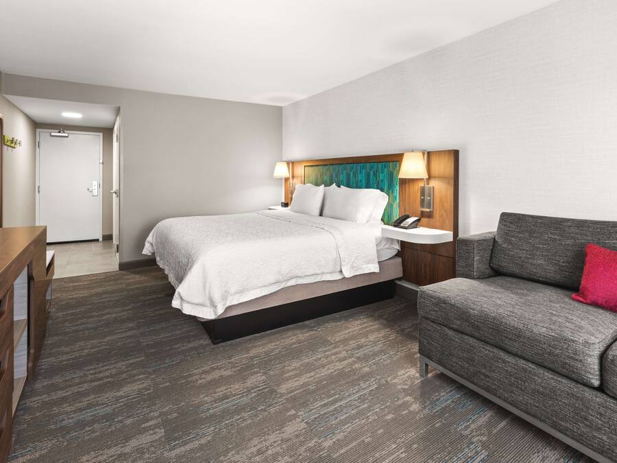 A hotel room with a bed, a sofa, a desk, and a nightstand.