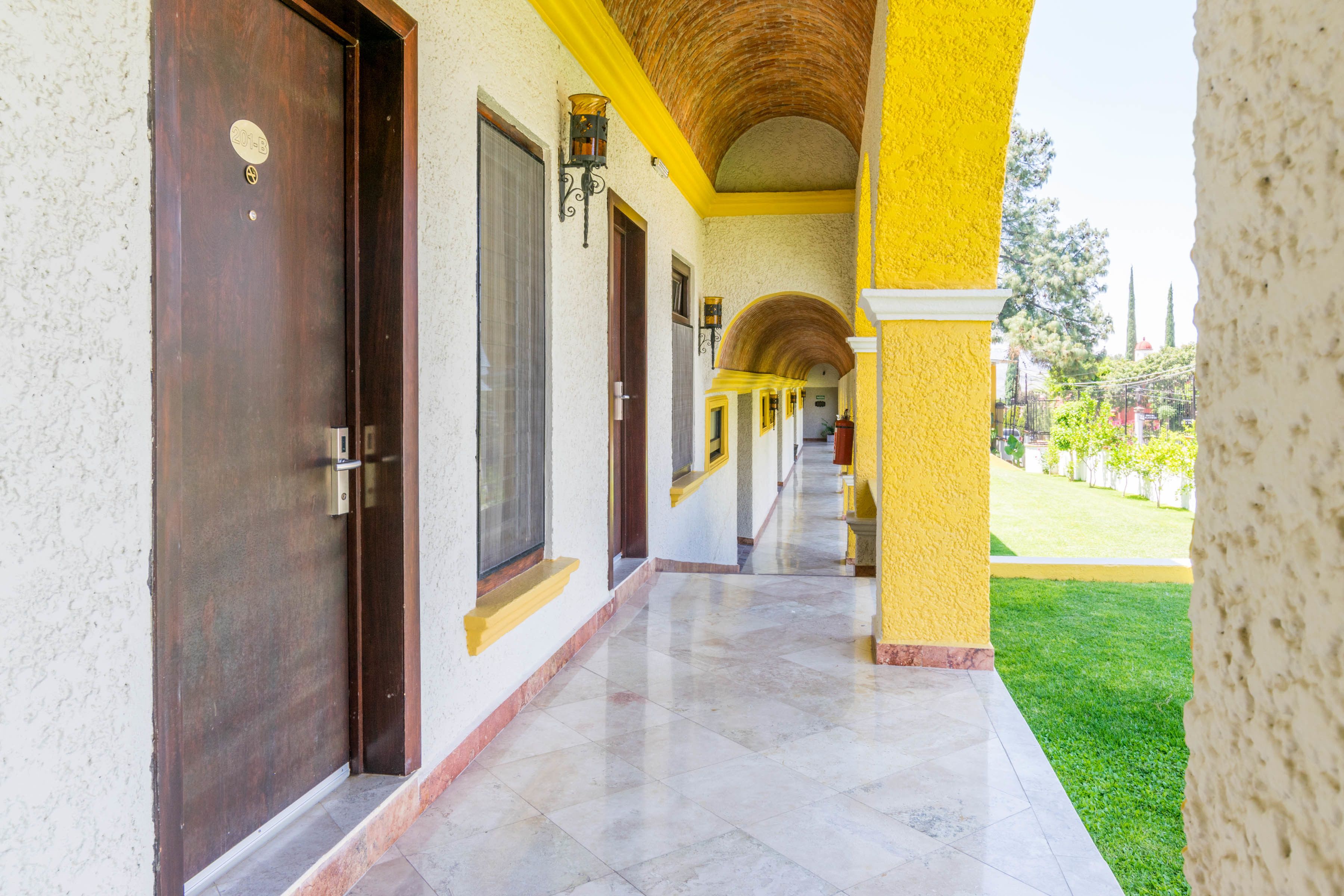 Un pasillo con puertas, paredes amarillas y suelo de baldosas.