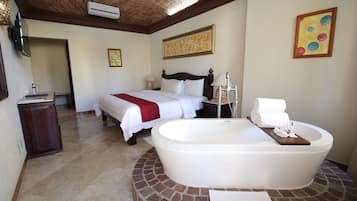 Un dormitorio amplio con una cama grande, un baño independiente con bañera exenta y una pared de ladrillo decorativa.