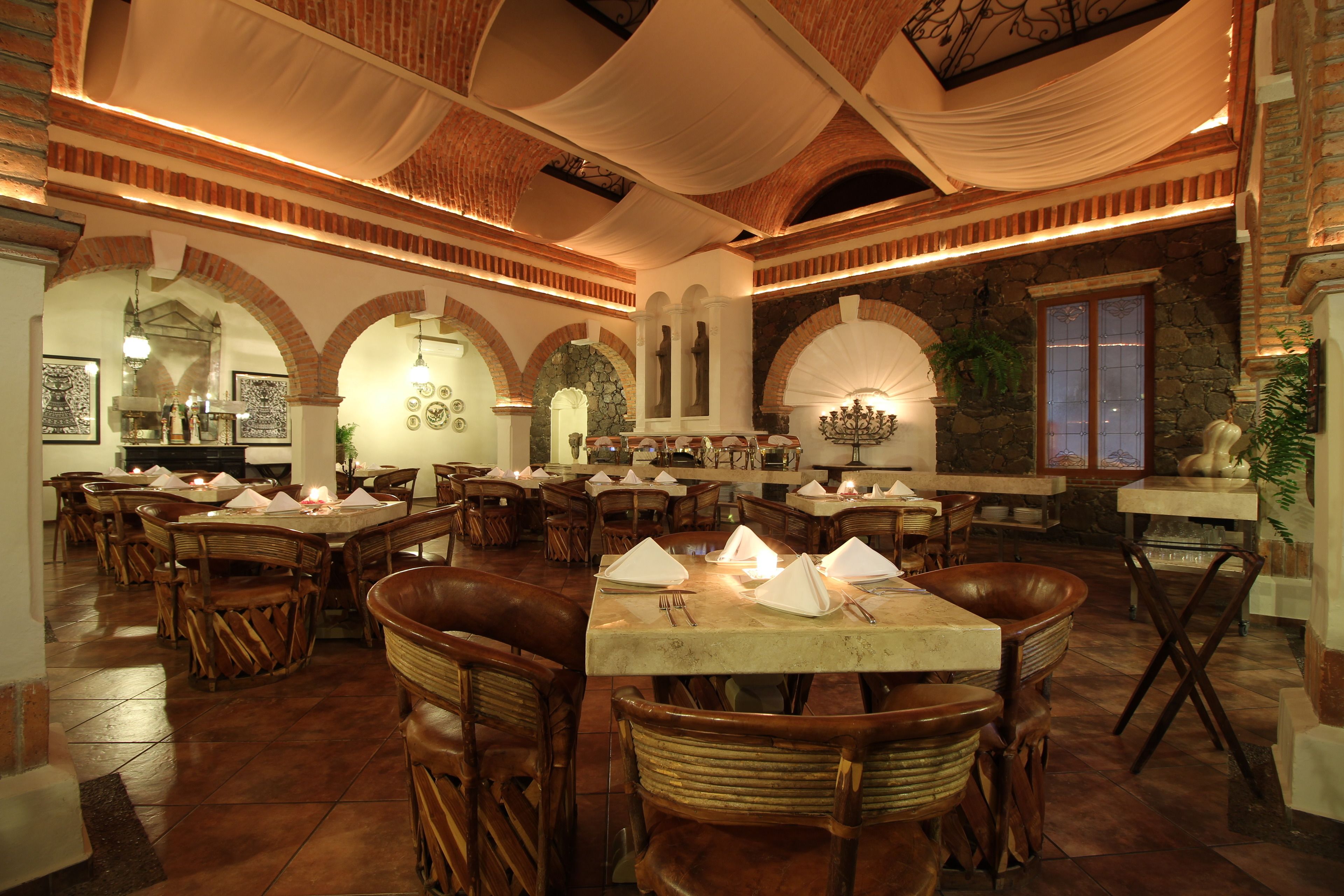 Ein Restaurant mit mehreren Tischen, Stühlen, Backsteinwänden und einem Steinkamin.