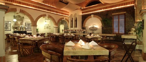 Ein Restaurant mit mehreren Tischen, Stühlen, Backsteinwänden und einem Steinkamin.