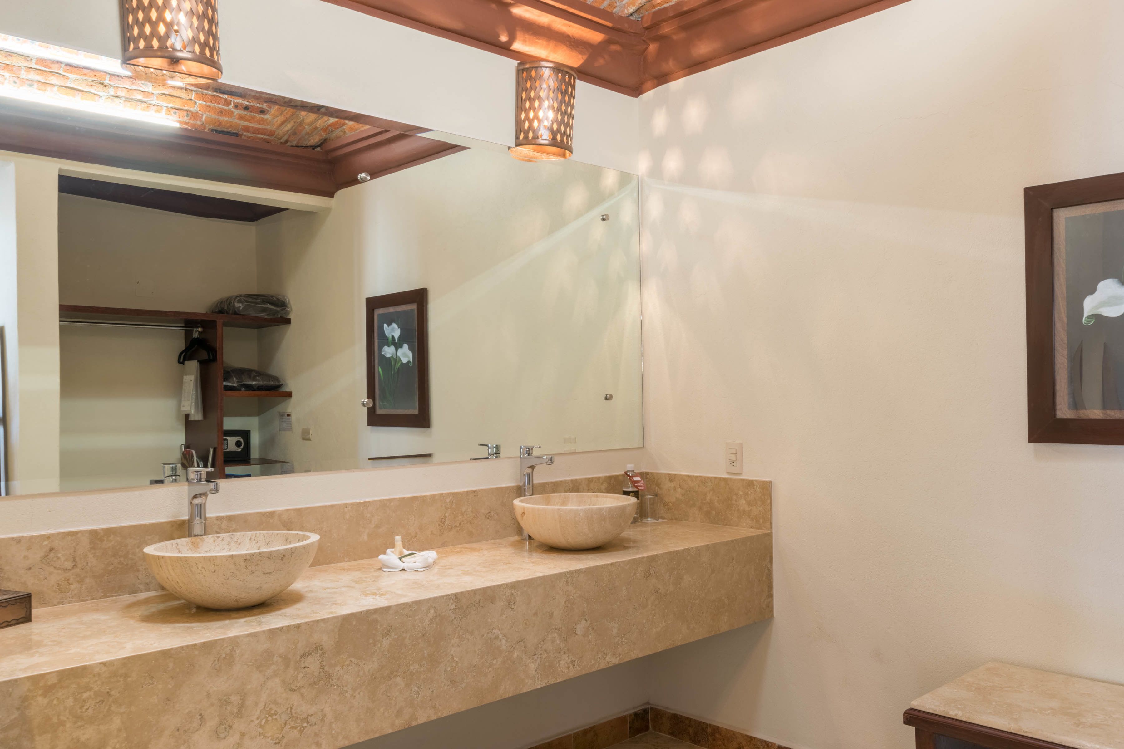 Un baño con dos lavamanos, un espejo grande y techo de madera.