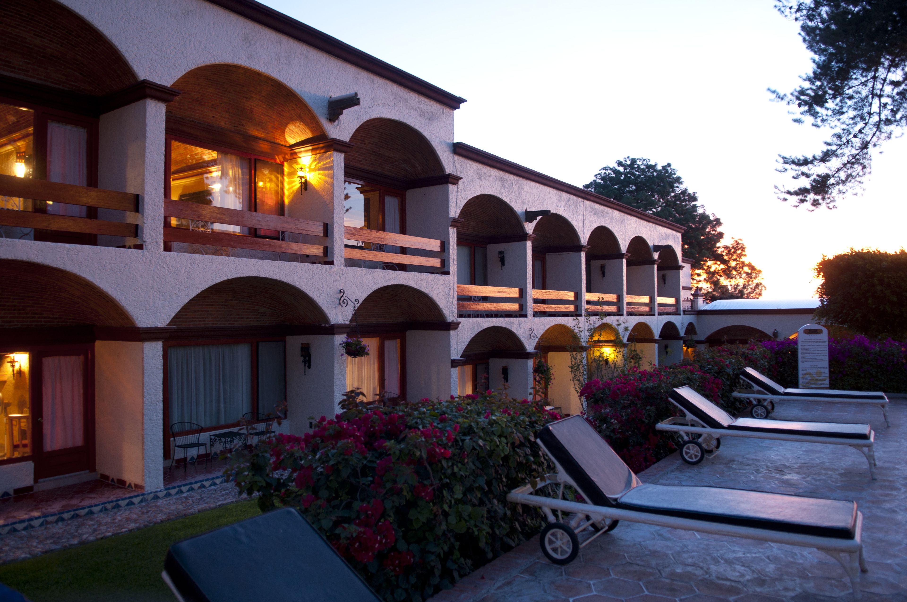 A hotel with multiple balconies, outdoor seating, and a garden area with flowers.