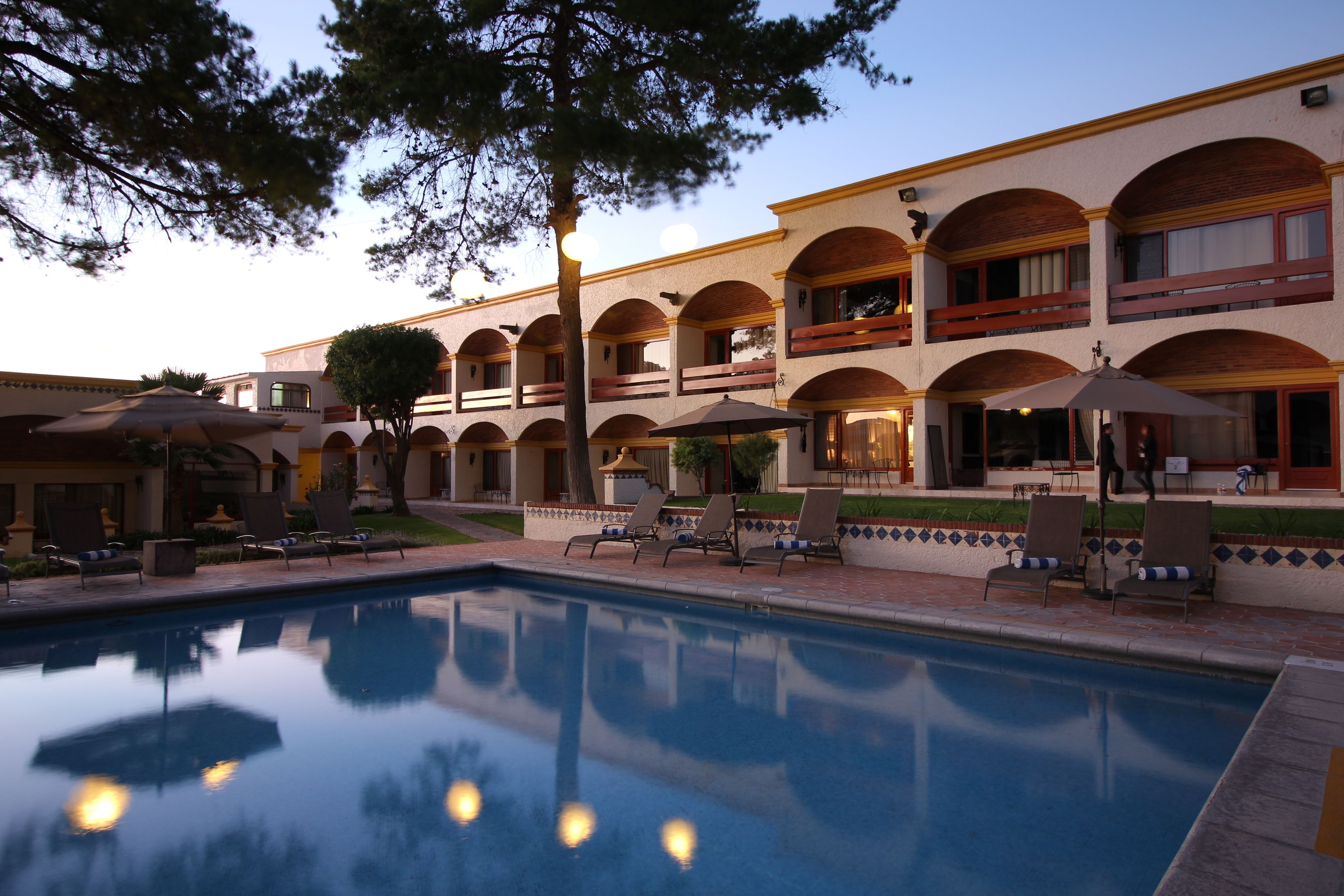 Ein Hotel mit Swimmingpool, Außenbereich zum Sitzen und einem zweistöckigen Gebäude mit Balkonen.