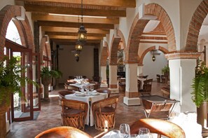 Un restaurante con arcos de ladrillo, muebles de madera y faroles colgantes.