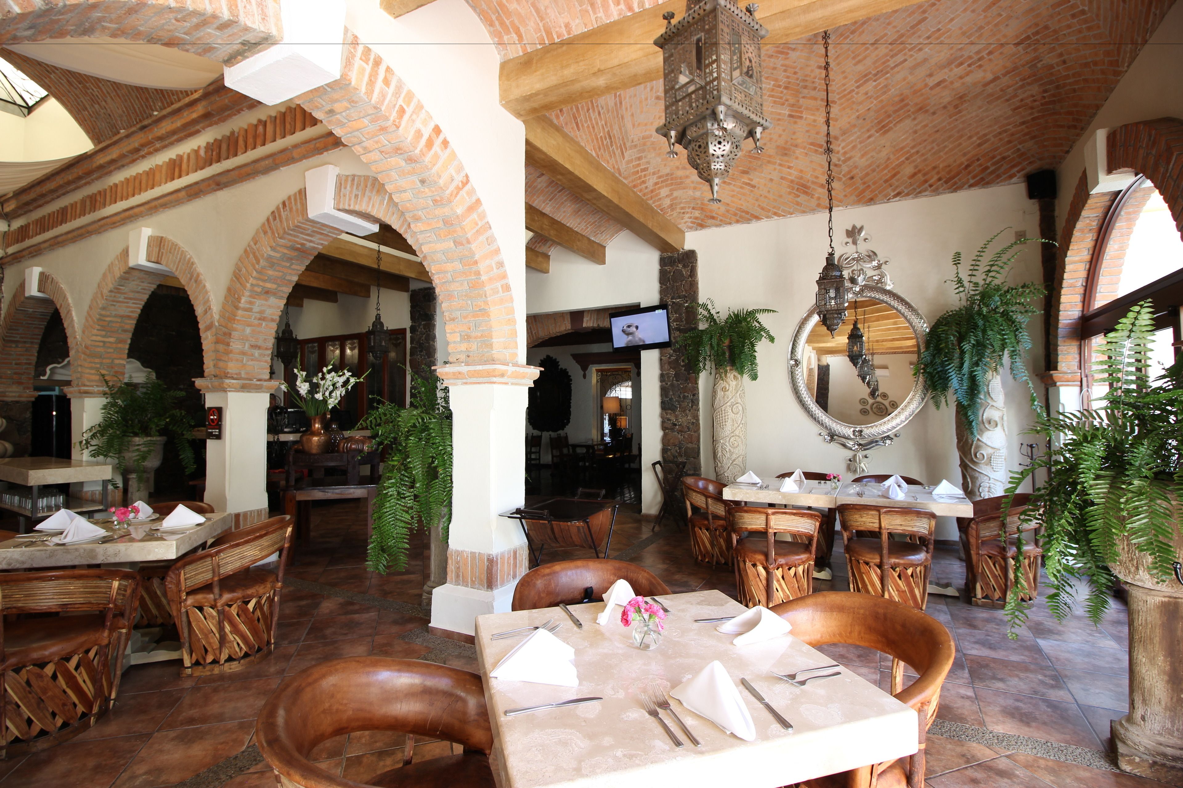 A restaurant with brick arches, wooden furniture, and hanging lanterns.