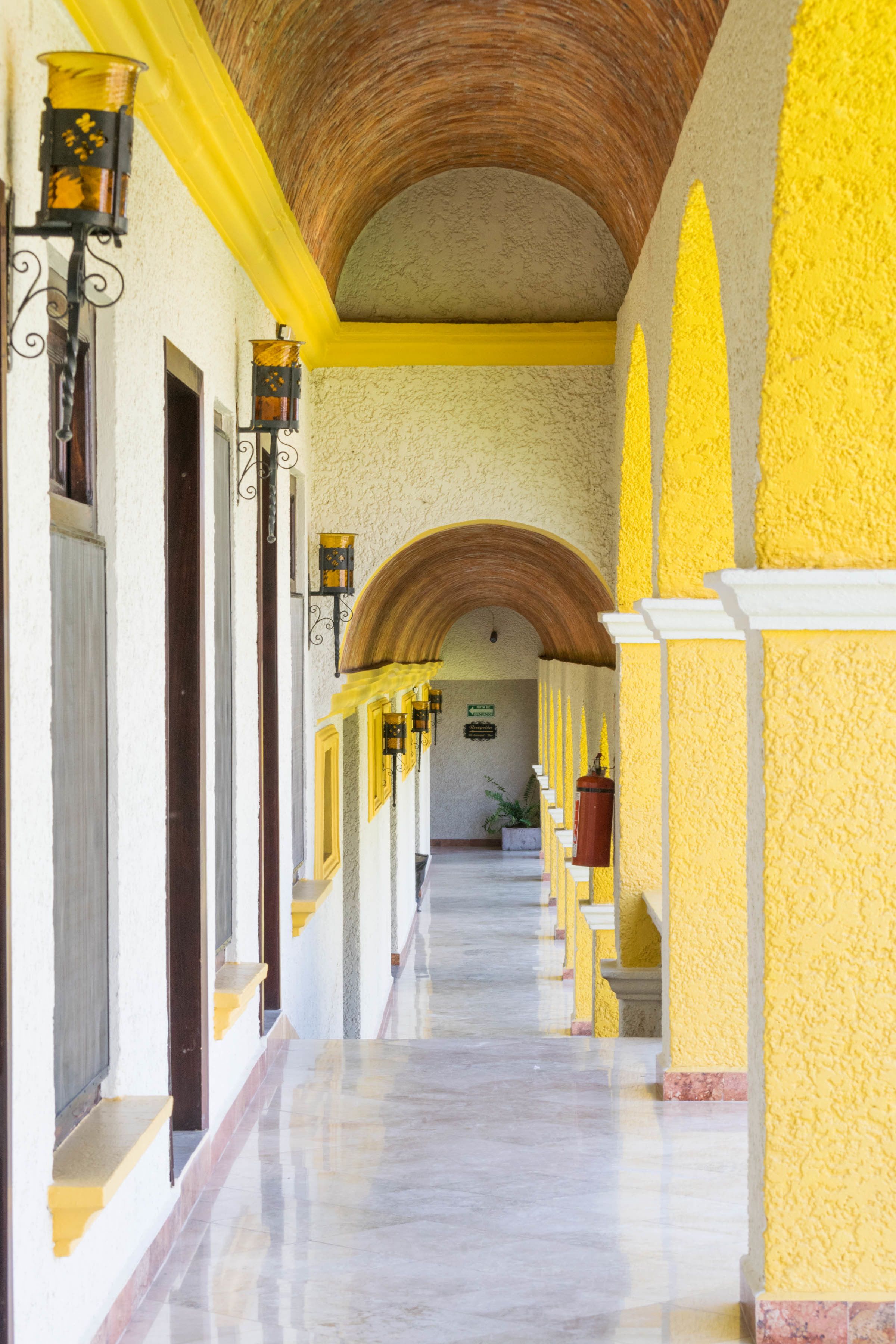 A corridor with yellow walls, white trim, and a tiled floor.
