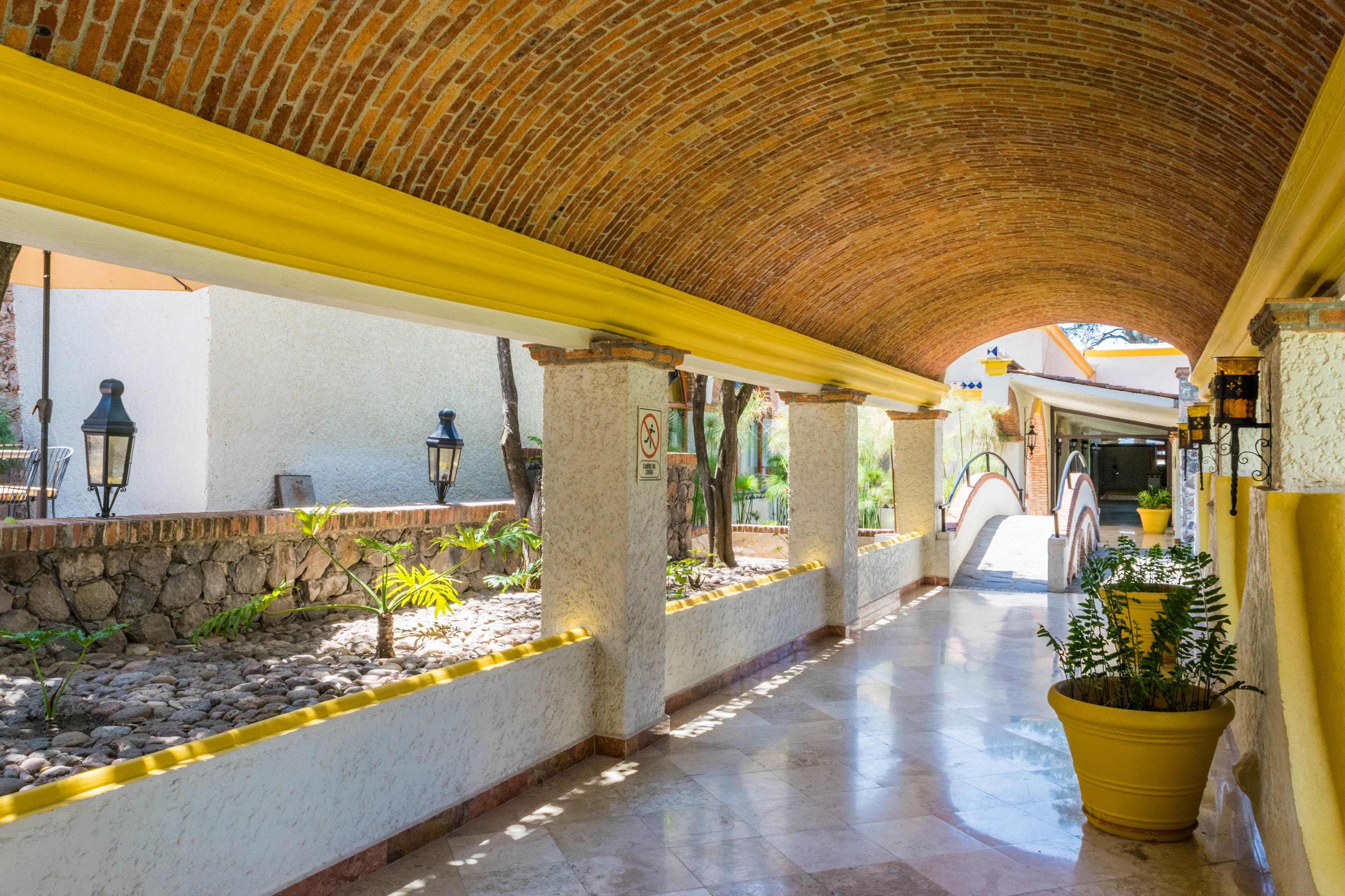 A covered corridor with a brick ceiling, stone walls, and yellow railings.