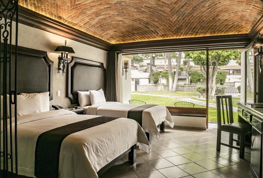 A hotel room with two beds, a balcony, and a view of the outside.