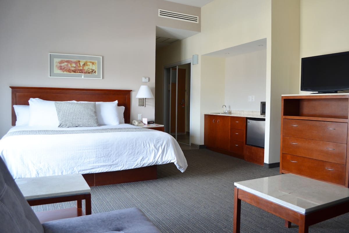 A hotel room with a large bed, a desk, a television, and a wardrobe.