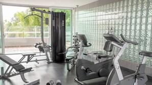 Academia moderna com equipamentos de cardio, halteres e um banco.