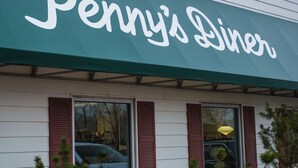 Un edificio con toldo verde que muestra el nombre 'Penny's Diner'.