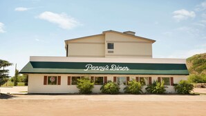 Un restaurante con dos pisos, toldo verde y un letrero que dice "Penny's Diner".