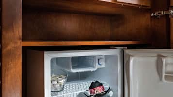 Una cocina con un microondas en el estante superior y un refrigerador con un peluche en el inferior.