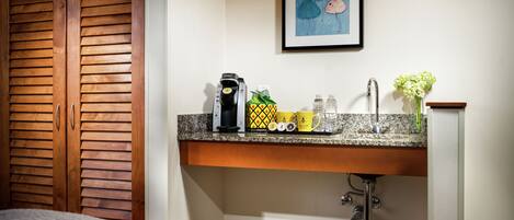 A bathroom with a wooden door, a sink with a faucet, a framed artwork on the wall, and toiletries on the countertop.