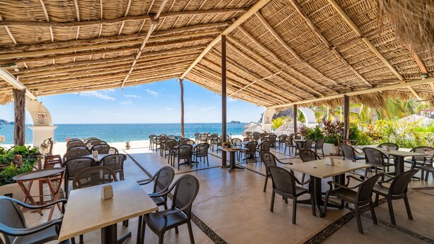 An outdoor dining area with tables and chairs, overlooking the ocean.