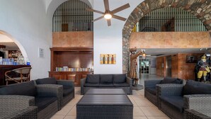 A spacious living area with wicker furniture, a ceiling fan, and a stone archway.