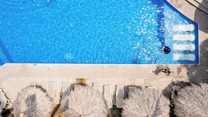 A swimming pool with clear blue water, lounge chairs, and a tiled deck.