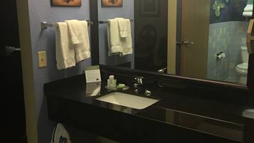A bathroom with a black sink, two white towels, a mirror, and a trash bin.