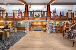 Um hall amplo com balcão de recepção, bandeiras americanas, um lustre e uma escadaria.