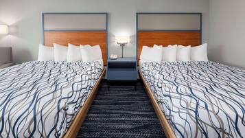 A hotel room with two beds, a nightstand with a lamp, and a carpeted floor.