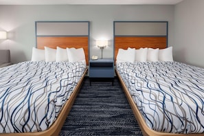 Ein Hotelzimmer mit zwei Betten, einem Nachttisch mit Lampe und Teppichboden.