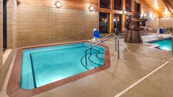 An indoor swimming pool with a wooden ceiling, tiled walls, and a bear statue.