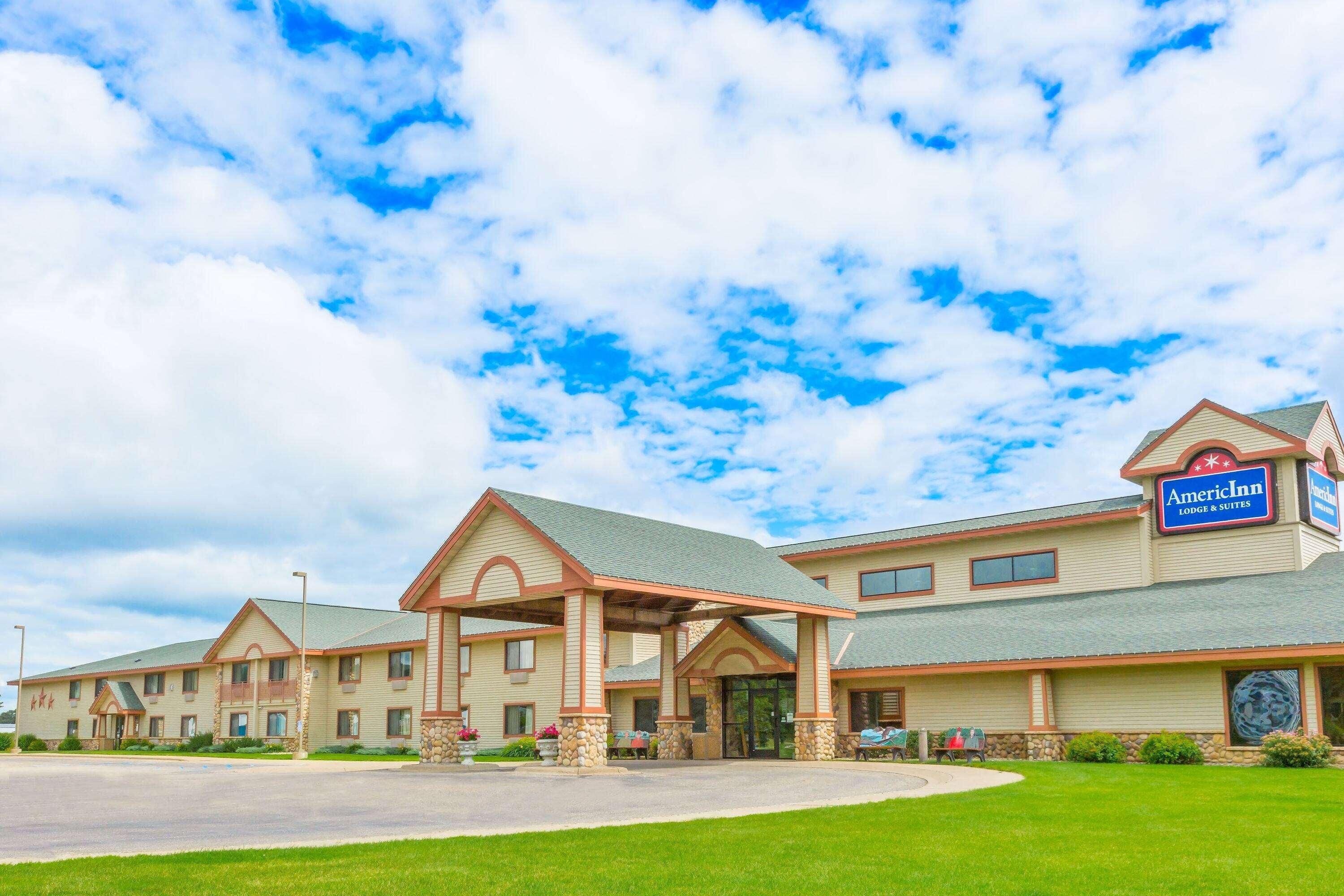A hotel with a covered entrance, multiple windows, and a sign indicating it is an American Inn.