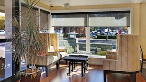 Een moderne woonkamer met een groot raam, een potplant, een bank, een salontafel en een fauteuil.