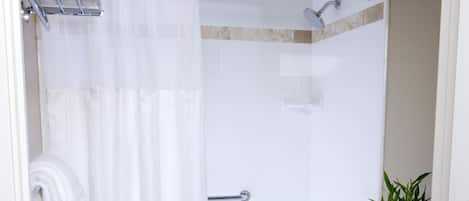 A bathroom with a shower, toilet, and a towel rack.