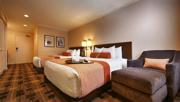 Habitación de hotel con dos camas, un sofá y una mesita.