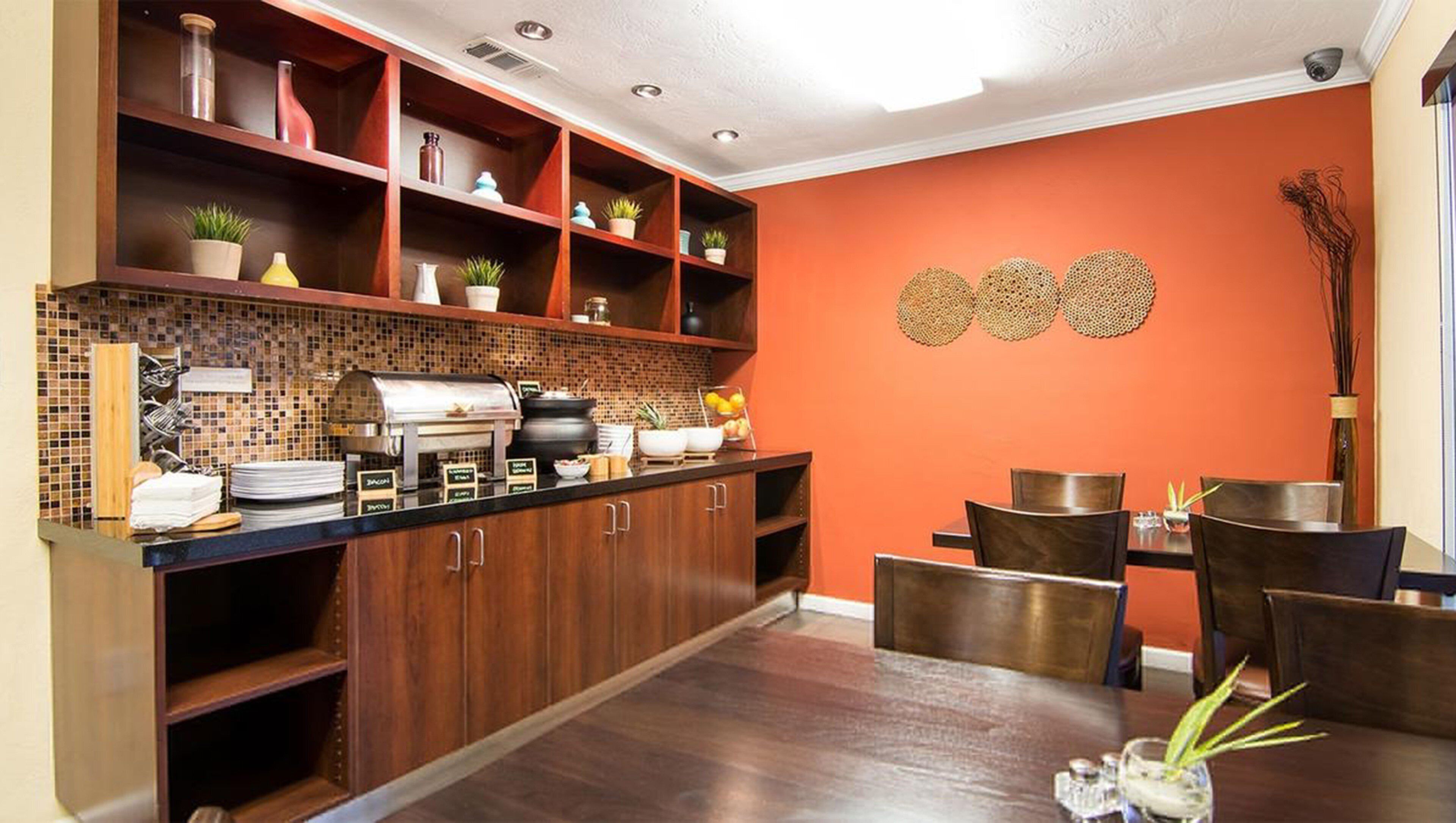 A modern kitchen with a buffet setup, wooden cabinets, and a tiled backsplash.