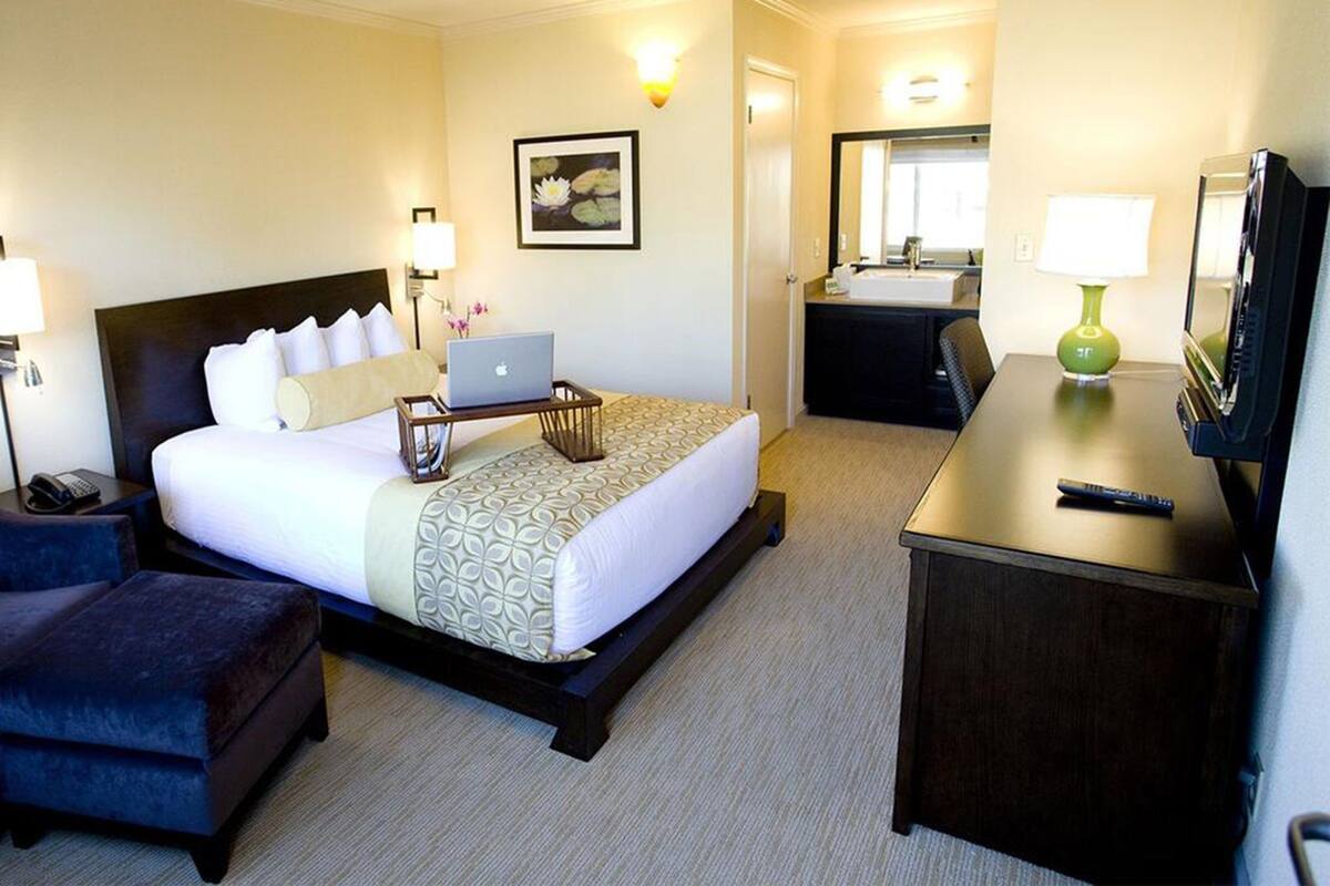 A hotel room with a bed, a desk, a chair, a TV, and a bathroom.
