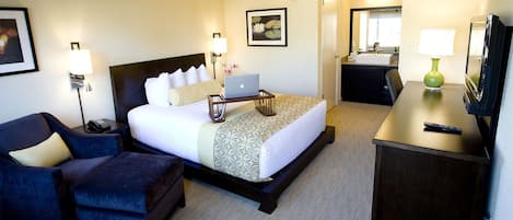 A hotel room with a bed, a desk, a chair, a TV, and a bathroom.