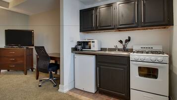 A compact kitchen with dark cabinets, a microwave, a gas stove, and a small refrigerator.