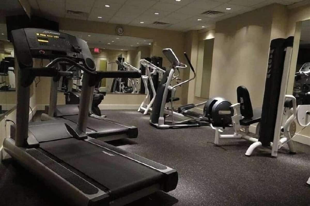 Une salle de sport équipée de tapis de course, de vélos elliptiques et d'appareils de musculation.