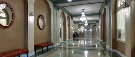 A spacious hallway with a polished floor, benches, and chandeliers.