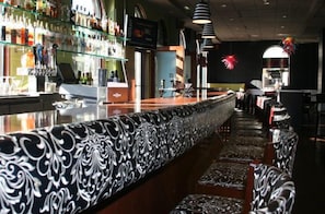 A bar area with a patterned counter, seating, and a display of bottles.
