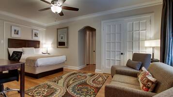 Habitación de hotel con cama, escritorio, silla, ventilador de techo y puerta.