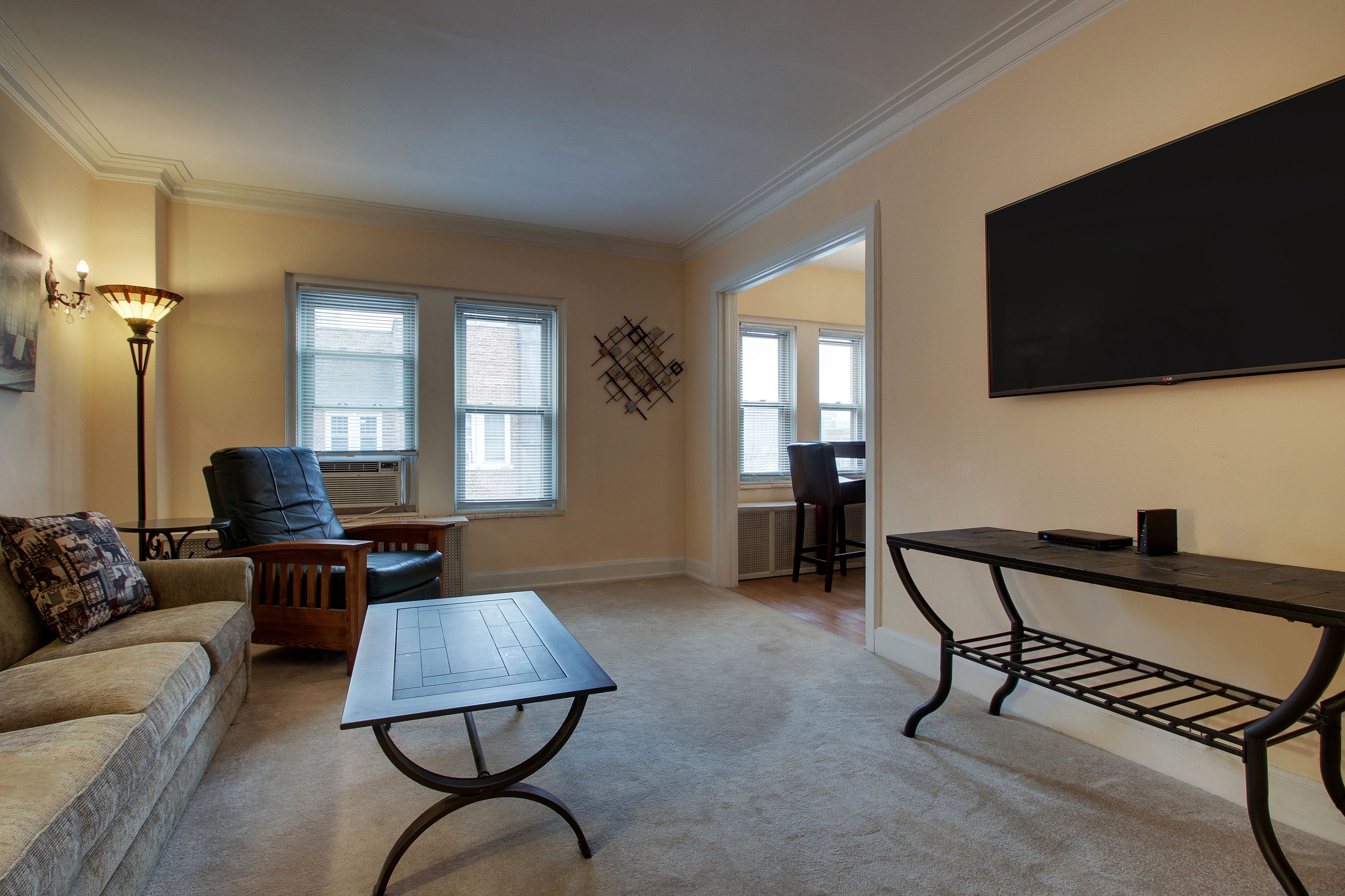 A living room with a sofa, a coffee table, a chair, a lamp, and a TV on a stand.
