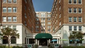 A multi-story hotel with a central entrance, brick facade, and a green awning with the number 1028.