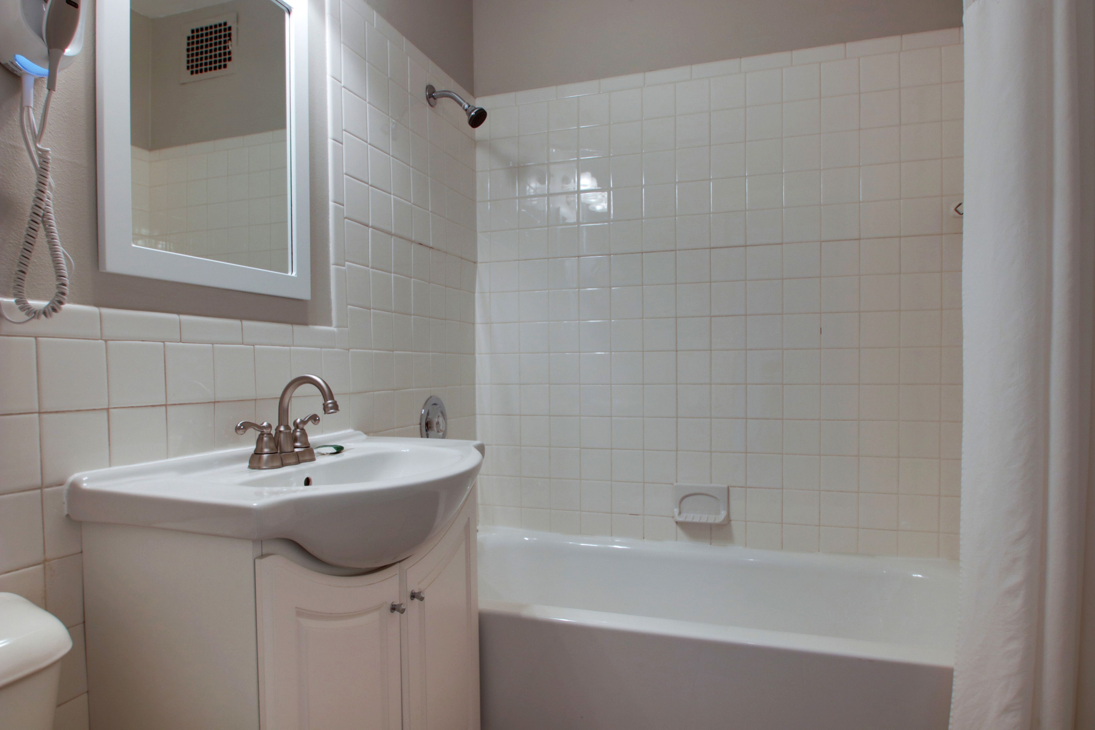 Ein Badezimmer mit weißem Waschbecken, Spiegel und Badewanne.