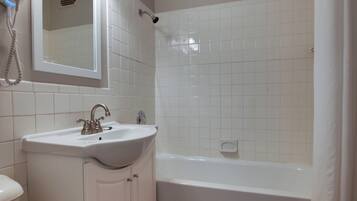 Ein Badezimmer mit weißem Waschbecken, Spiegel und Badewanne.