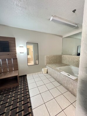A bathroom with a bathtub, a mirror, a vanity, and a shower area. - Country Hearth Inn & Suites Augusta (Augusta)