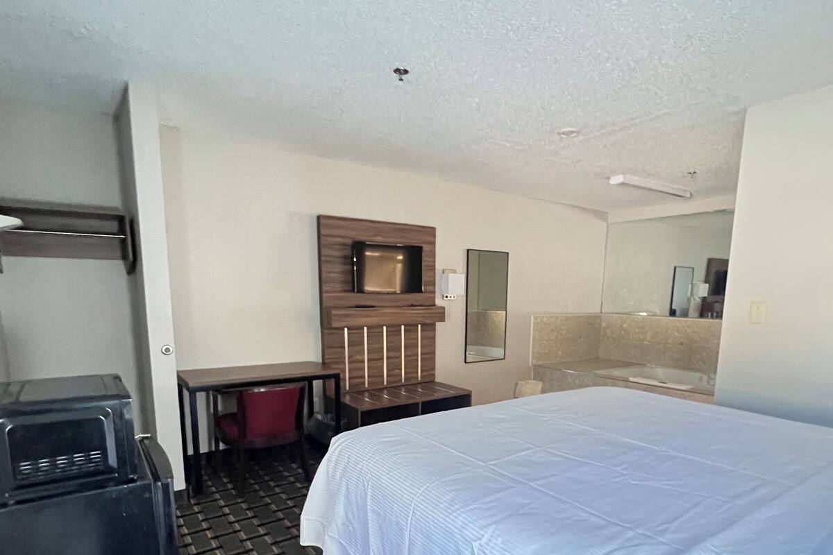 A hotel room with a bed, a desk, a TV, and a minibar.