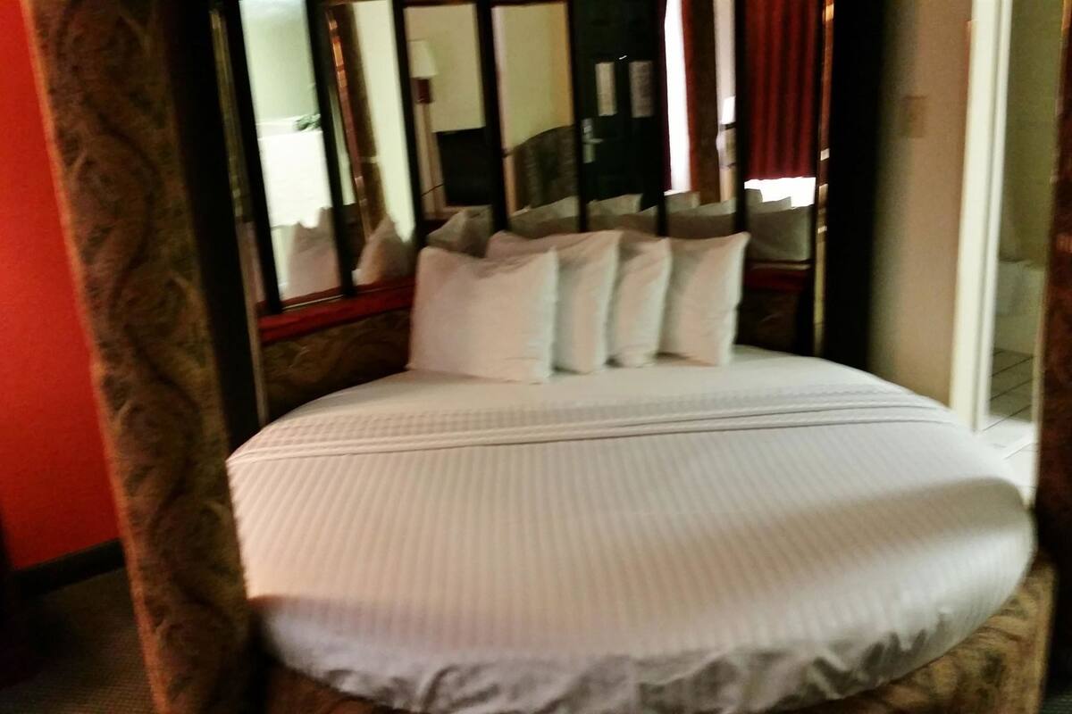 A bed with white bedding, a wooden headboard, and a glass door leading to a balcony.