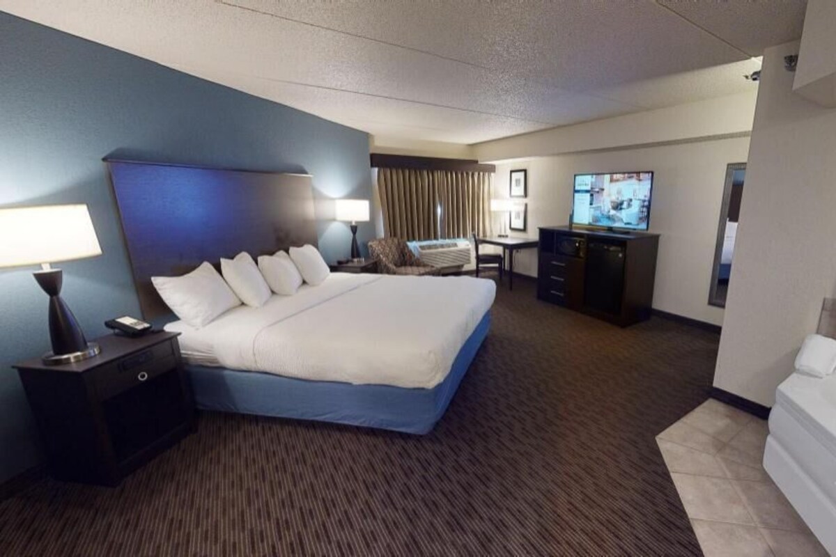 Een hotelkamer met een groot bed, een bureau, een televisie en een bad.