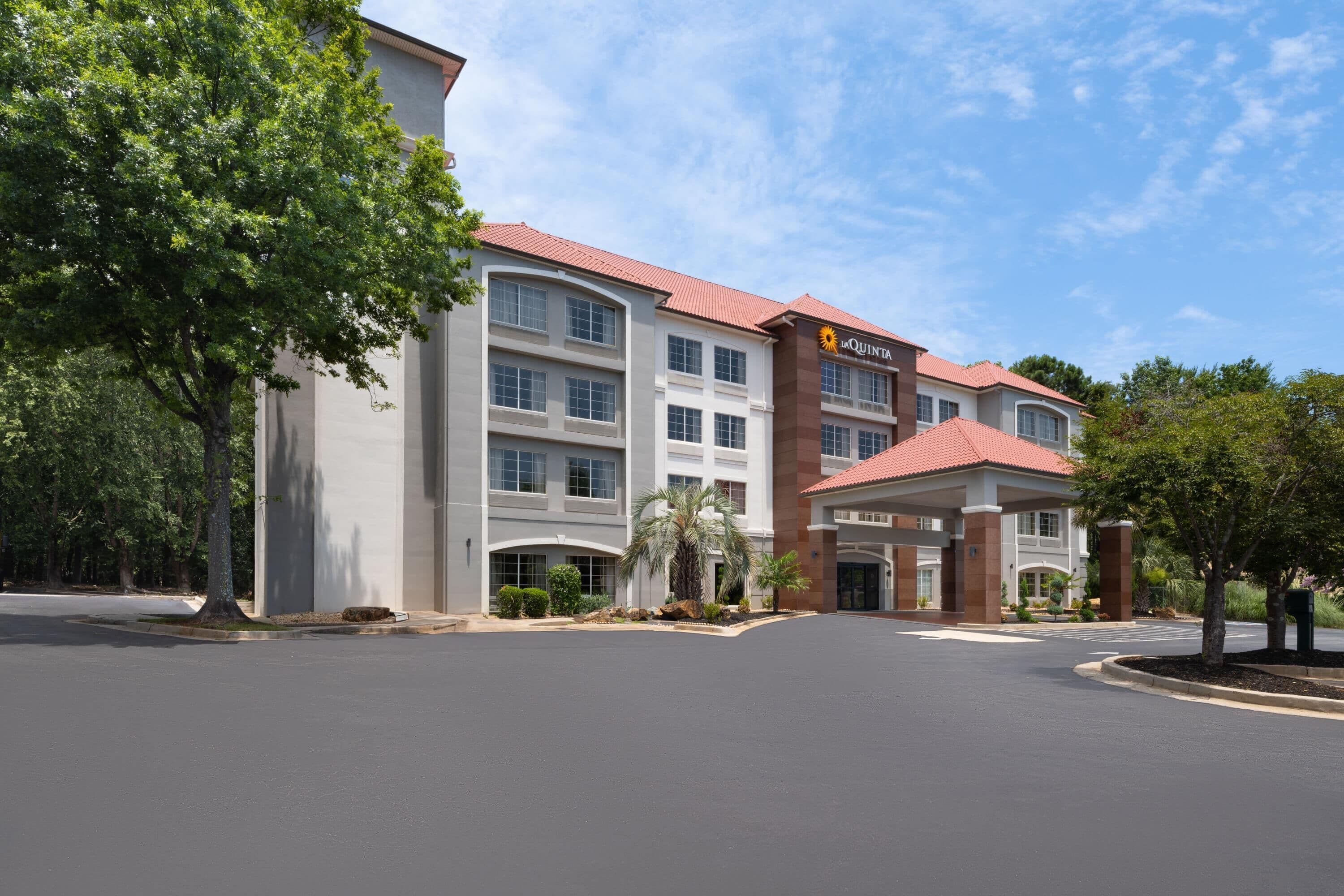 A hotel with a red roof, multiple floors, and a central entrance with a covered area.